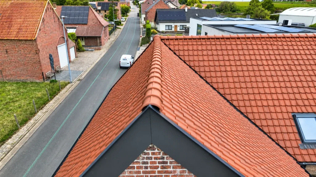 Dakrenovatie Geraardsbergen: de nieuwe rode dakpannen en nokpannen boven de straat