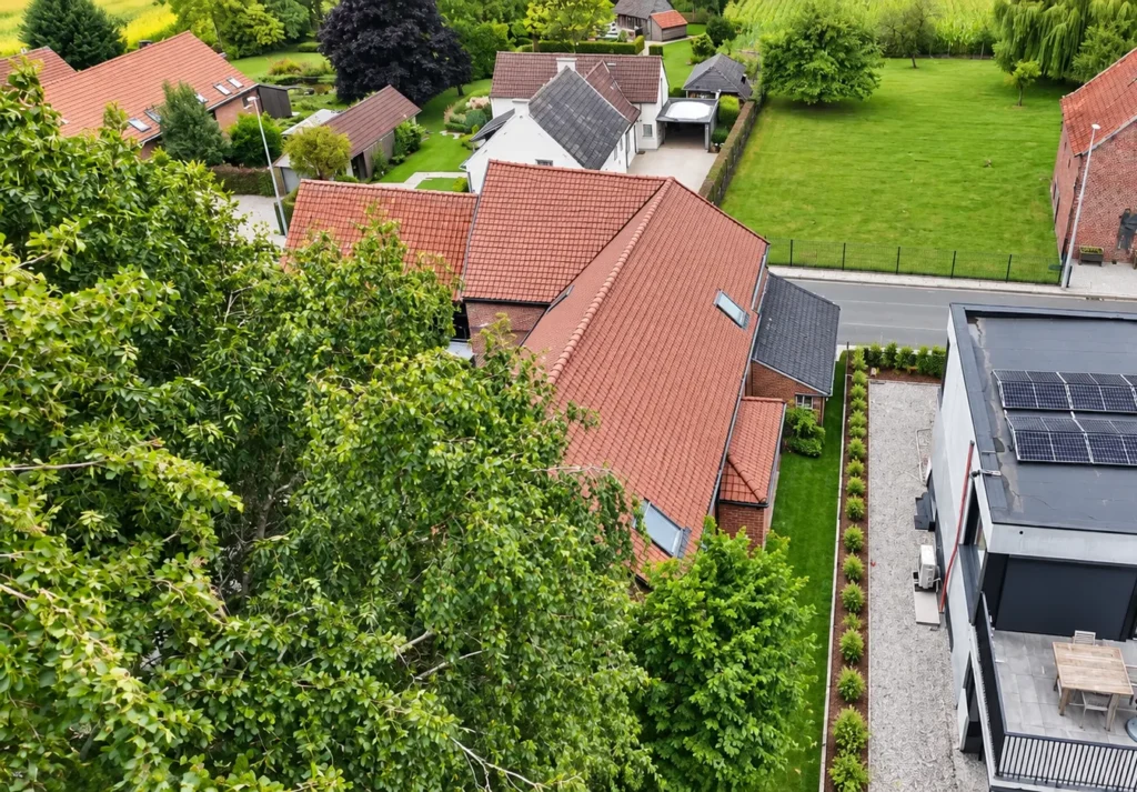 Dakrenovatie Geraardsbergen: de woning met het nieuwe dak tussen het groen