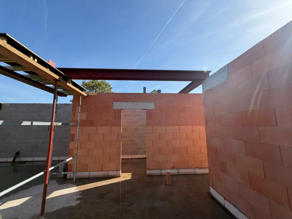 Binnenzicht van een nieuwbouw in ruwbouw met stalen liggers en een deuropening met betonlatei